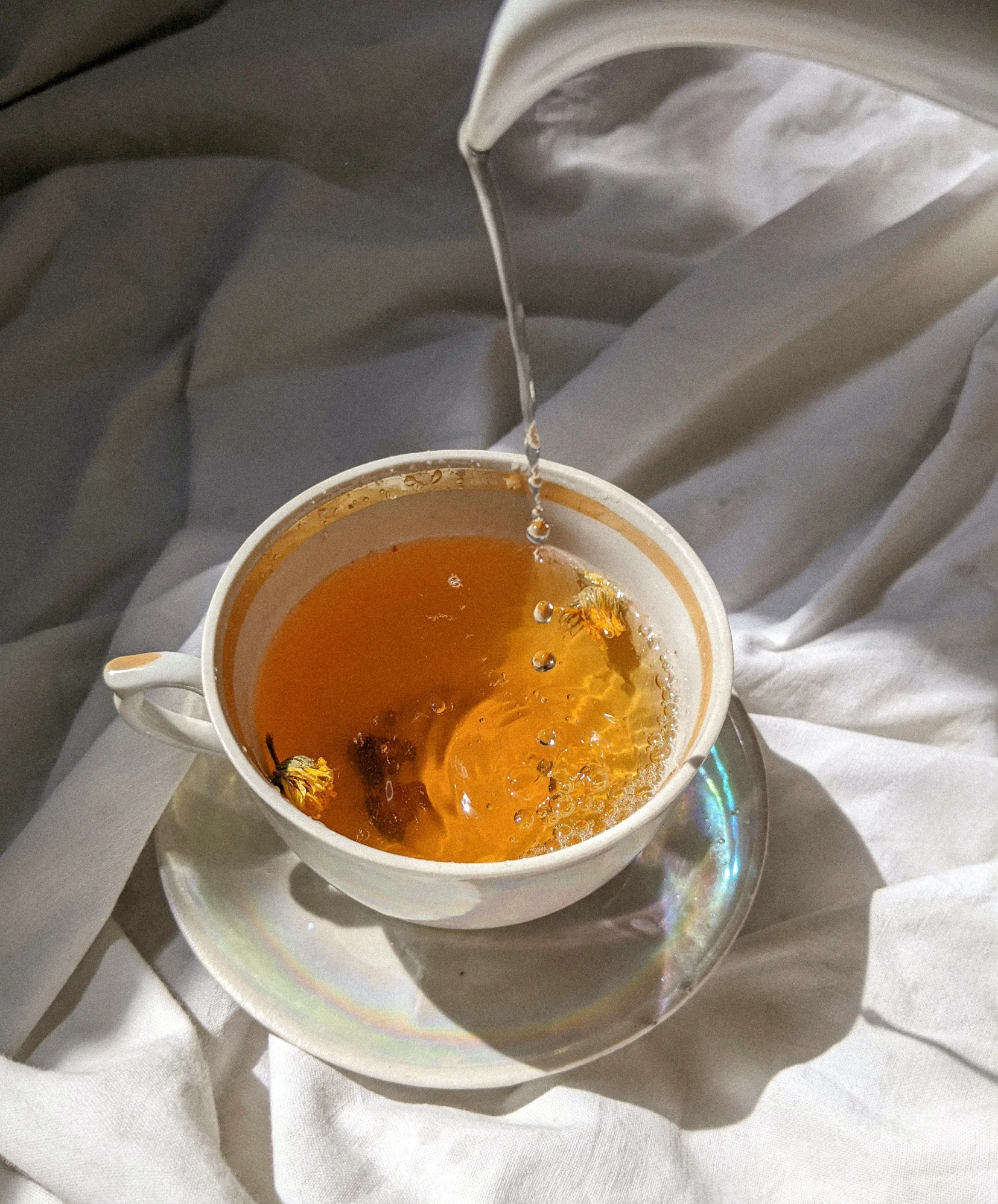 Tasse de thé Teas délicatement posée sur un lit, illuminée par un rayon de soleil. La scène évoque une atmosphère chaleureuse et relaxante, invitant à la douceur d'un moment de bien-être.